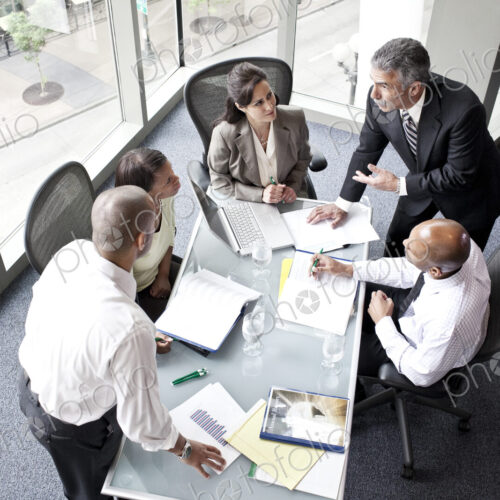 Male and female business people in a meeting at a conference table, overhead view Male and female business people in a meeting at a conference table, overhead view