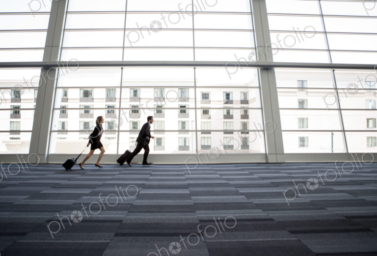 Male and female business people running past a window in the lobby of a conference centre