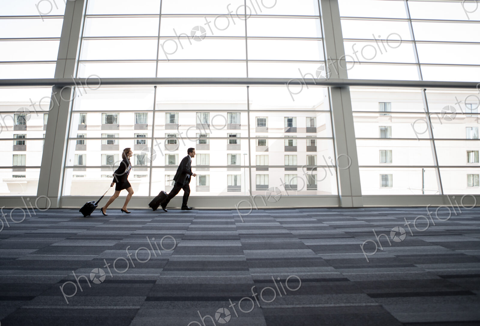 Male and female business people running past a window in the lobby of a conference centre