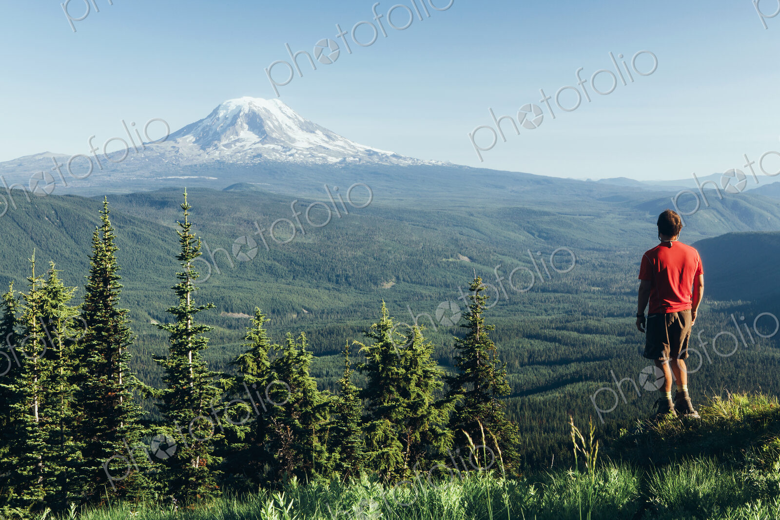 Male hiker on a mountain summit, looking at the landscape towards Mount Hood