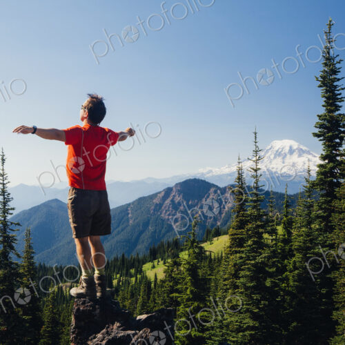 Male hiker standing with his arms outstretched on a mountain top, looking over the… Male hiker standing with his arms outstretched on a mountain top, looking over the…