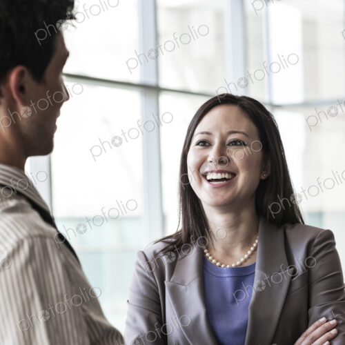 Man and woman businesspeople chatting in a large lobby area.