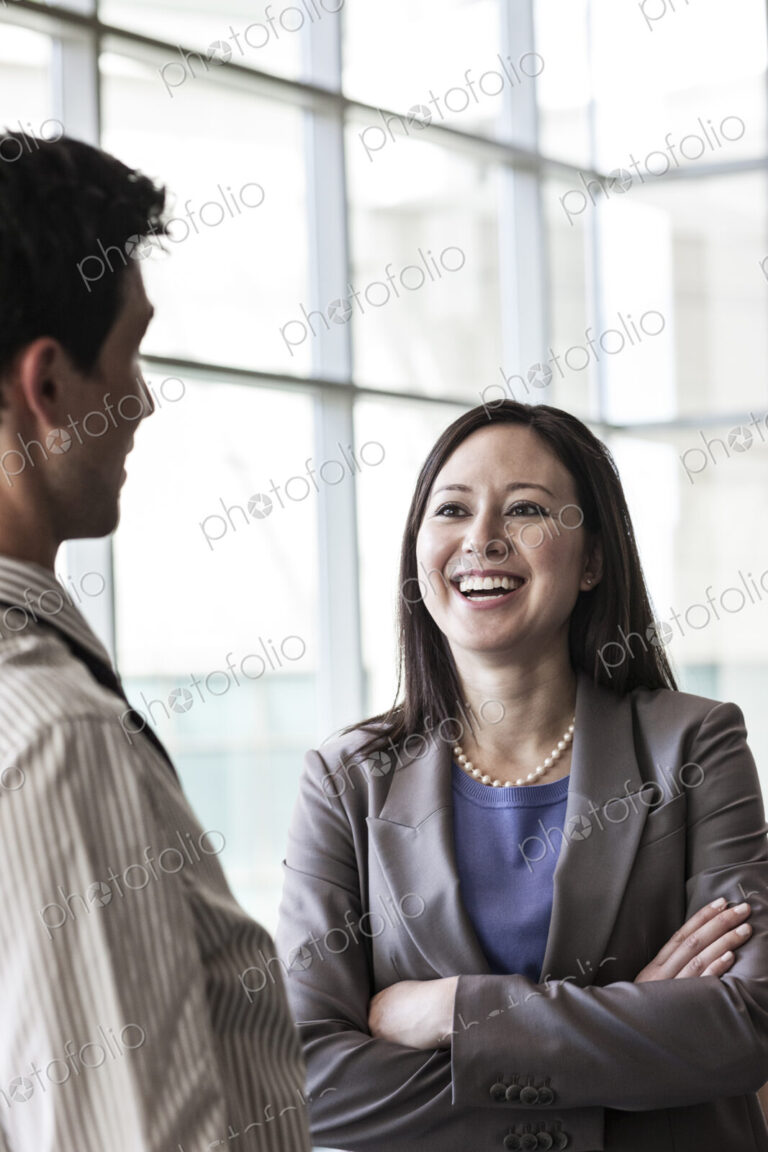 Man and woman businesspeople chatting in a large lobby area.