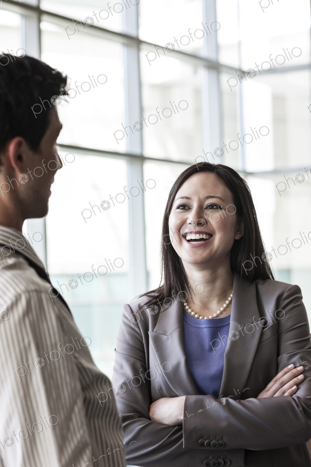Man and woman businesspeople chatting in a large lobby area.