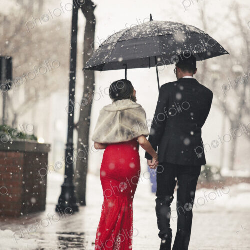 Man and woman, couple in evening dress outside in a city in snow