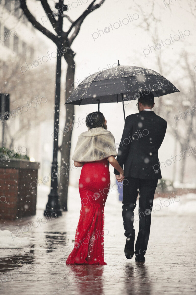 Man and woman, couple in evening dress outside in a city in snow