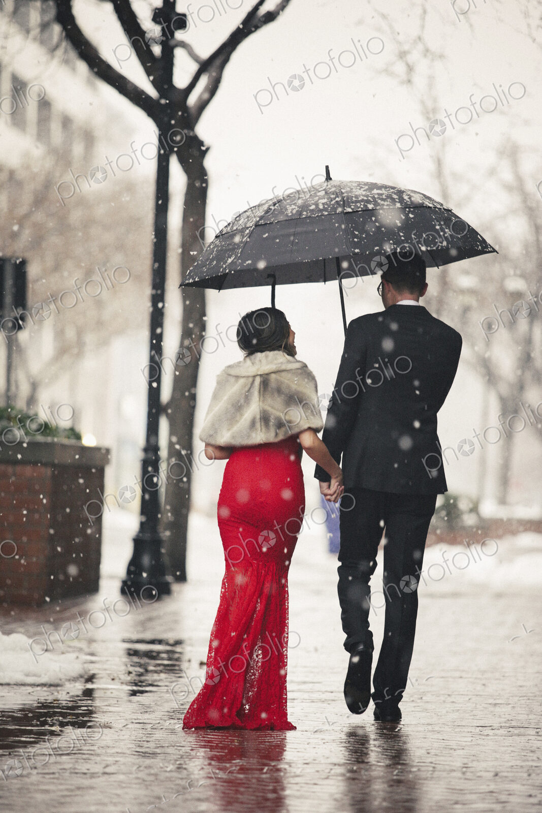Man and woman, couple in evening dress outside in a city in snow