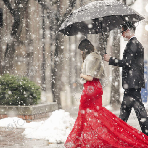 Man and woman, couple in evening dress outside in a city in snow