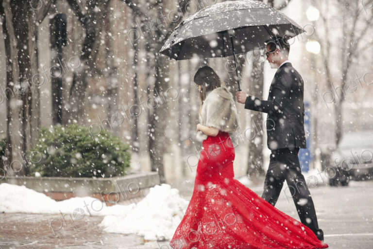 Man and woman, couple in evening dress outside in a city in snow