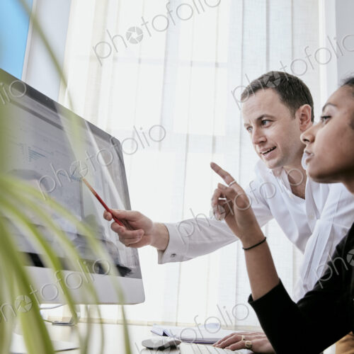 Man and woman discussing data on a large computer screen Man and woman discussing data on a large computer screen