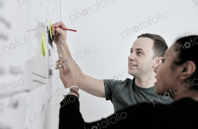 Man and woman discussing work and making notes on a whiteboard. in an office.