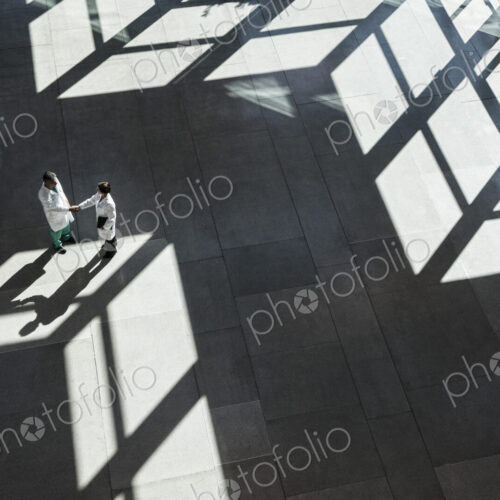 Man and woman doctors conferring over medical records in a hospital lobby. Man and woman doctors conferring over medical records in a hospital lobby.