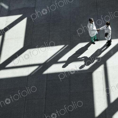 Man and woman doctors conferring over medical records in a hospital lobby. Man and woman doctors conferring over medical records in a hospital lobby.