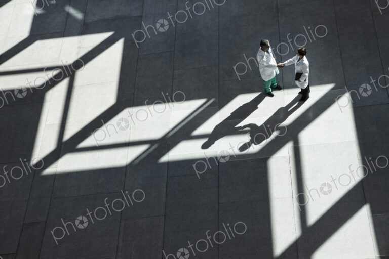 Man and woman doctors conferring over medical records in a hospital lobby.