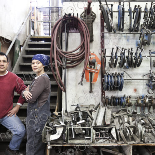 Man and woman mixed race team of workers in a large sheet metal factory Man and woman mixed race team of workers in a large sheet metal factory