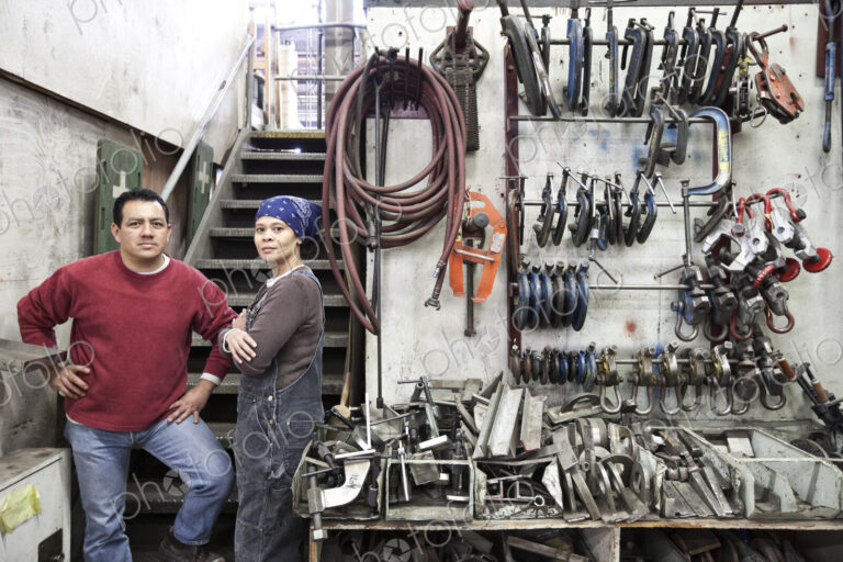Man and woman mixed race team of workers in a large sheet metal factory