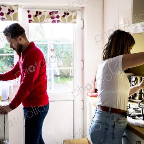 Man and woman standing in a domestic kitchen, making jar candles. Man and woman standing in a domestic kitchen, making jar candles.