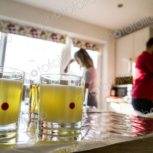 Man and woman standing in a domestic kitchen, making jar candles. Man and woman standing in a domestic kitchen, making jar candles.