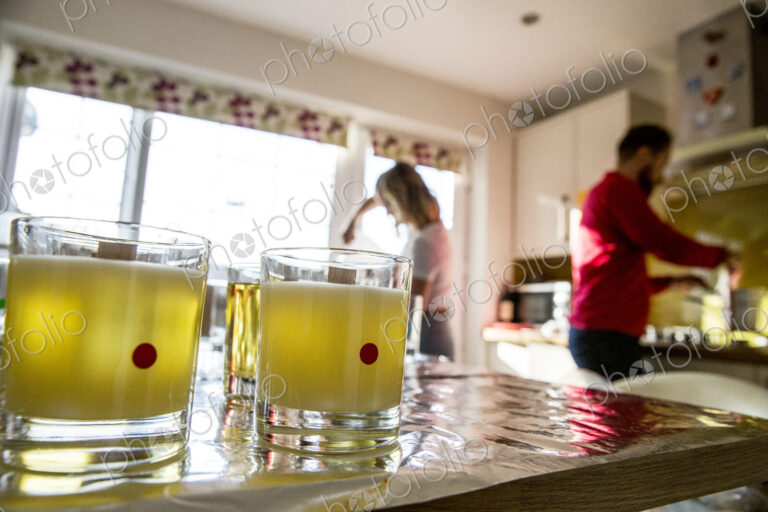 Man and woman standing in a domestic kitchen, making jar candles.