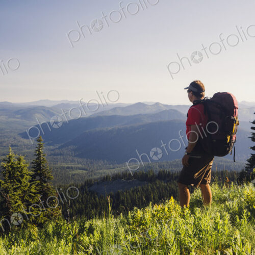Man backpacking in the mountains, walking on a ridge overlooking a valley. Man backpacking in the mountains, walking on a ridge overlooking a valley.