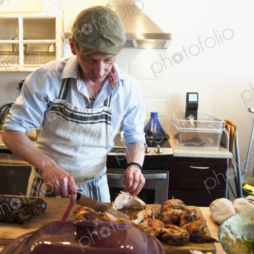 Man carving roasted meat in kitchen