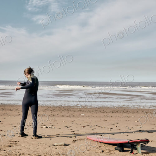 Man exercising, stretching and warming up on a sandy beach before surfing Man exercising, stretching and warming up on a sandy beach before surfing
