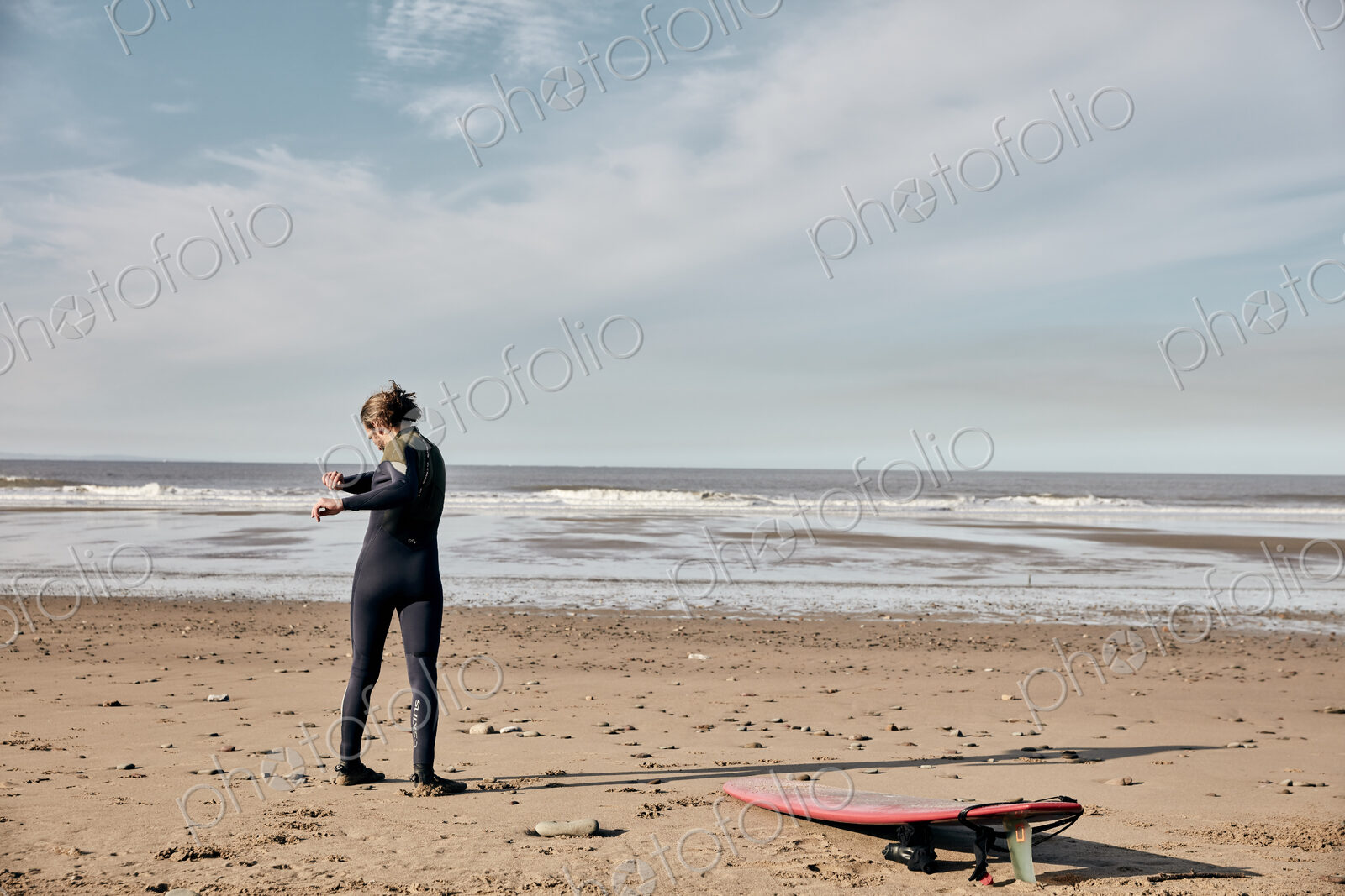 Man exercising, stretching and warming up on a sandy beach before surfing