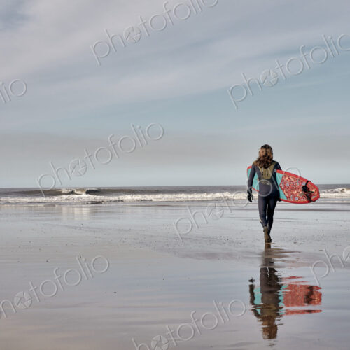 Man holding a surf board walking out to the sea at low tide. Man holding a surf board walking out to the sea at low tide.