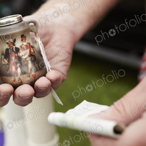 Man holding a vintage pot and British currency, cash, at a flea market.