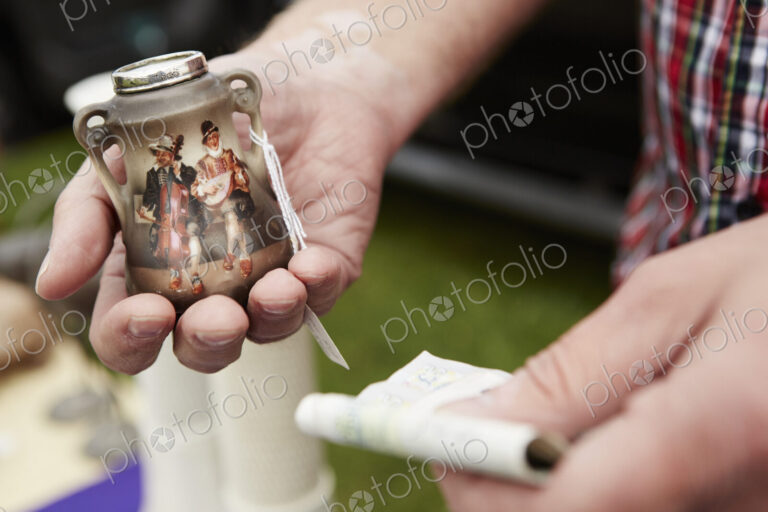 Man holding a vintage pot and British currency, cash, at a flea market.