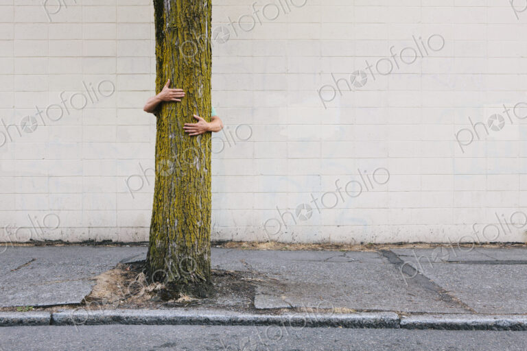 Man hugging tree on urban street and sidewalk