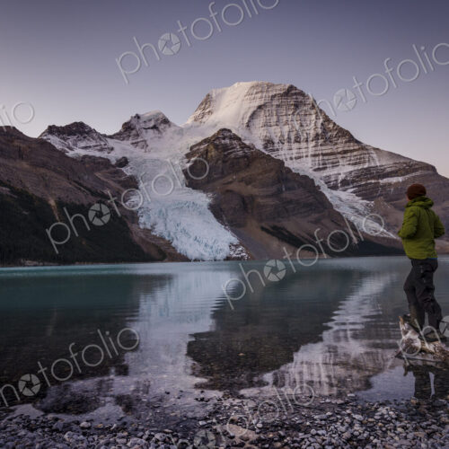 Man looking at Mount Robson above Berg lake at dawn.