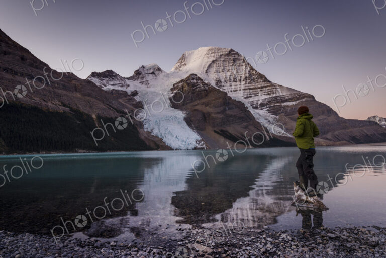 Man looking at Mount Robson above Berg lake at dawn.
