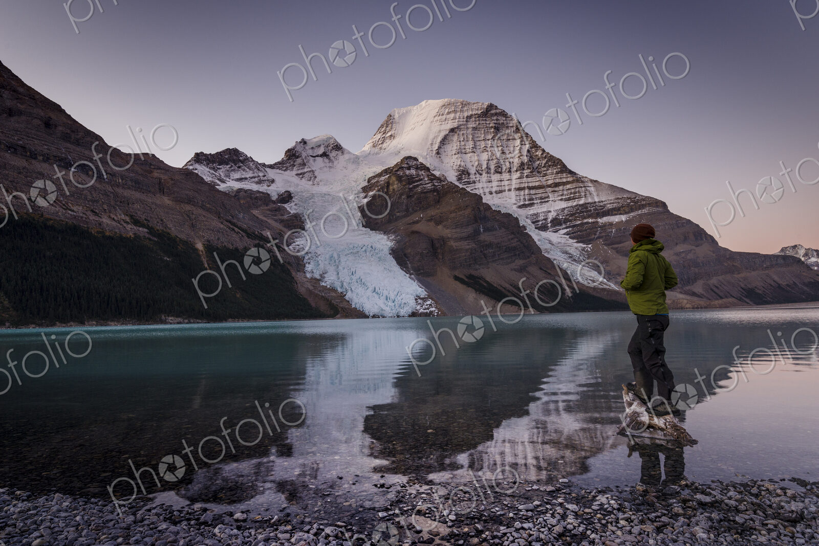 Man looking at Mount Robson above Berg lake at dawn.