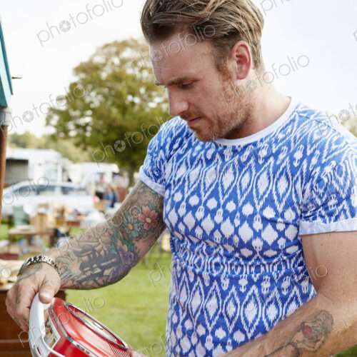 Man looking at a red vintage radio at a flea market. Man looking at a red vintage radio at a flea market.