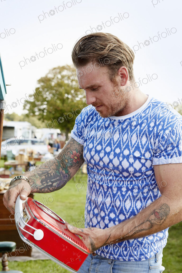 Man looking at a red vintage radio at a flea market.