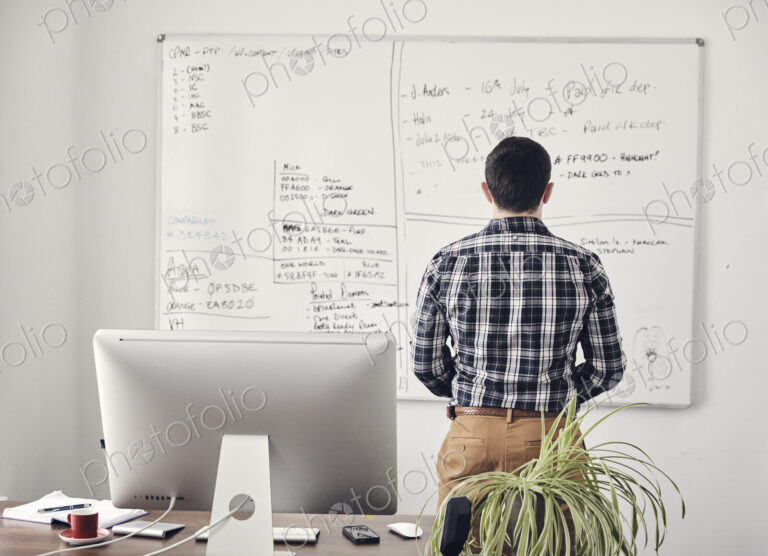 Man looking at a whiteboard in office with his back to camera