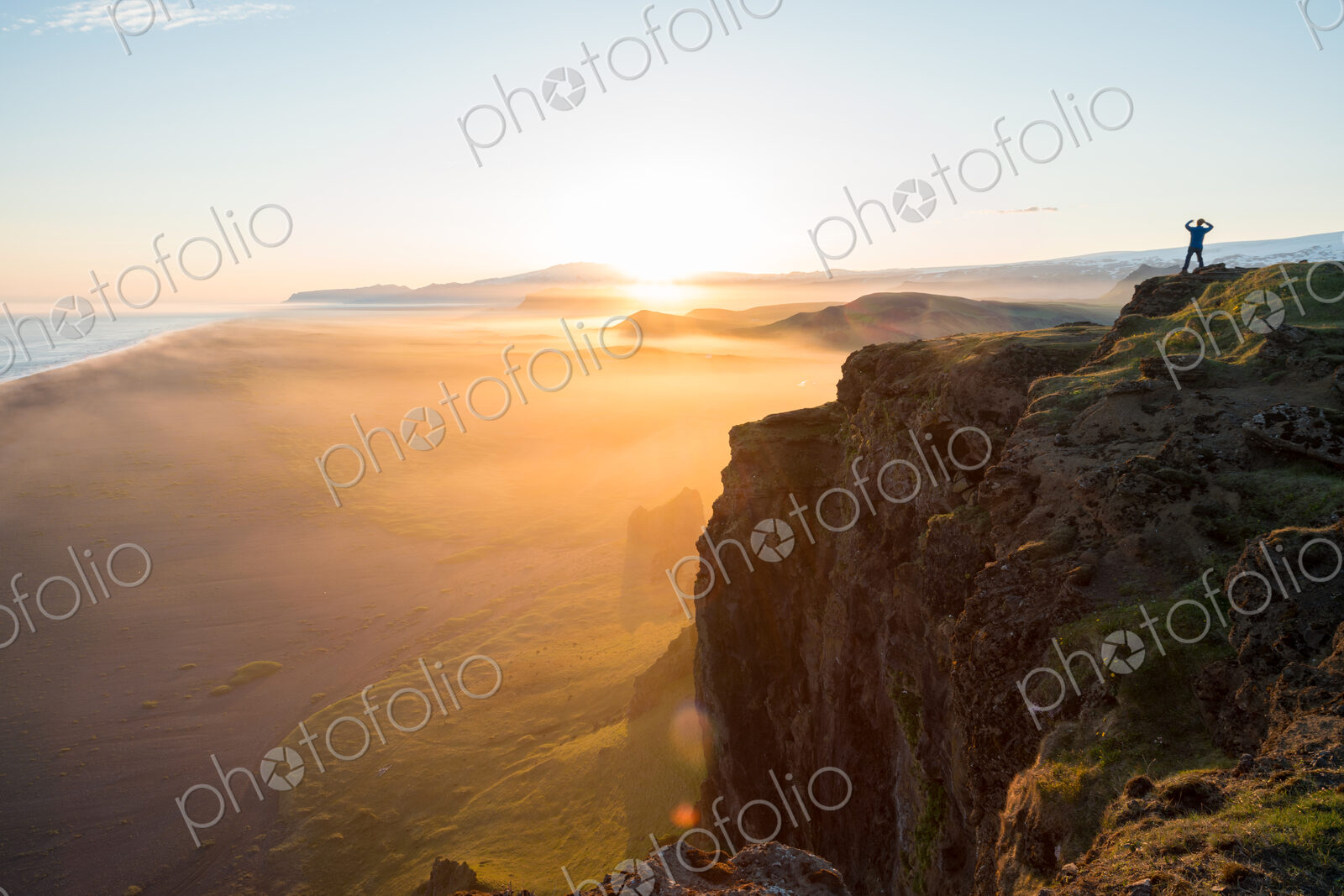 Man looking at the view at sunset from Dyrholaey Peninsula, near Vik, South Iceland…