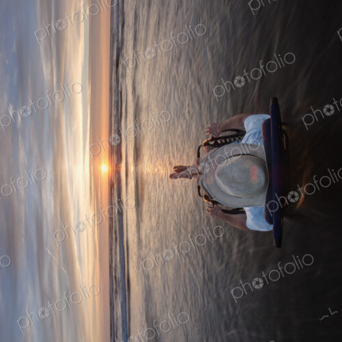 Man lying in sun lounger in shallow wave at beach at sunset. Man lying in sun lounger in shallow wave at beach at sunset.