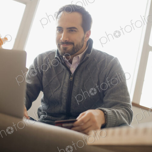 Man on-line shopping on laptop on sofa with credit card Man on-line shopping on laptop on sofa with credit card