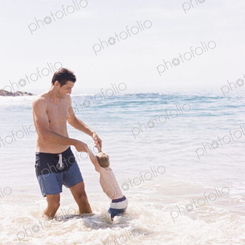 Man playing with his young son on the beach.