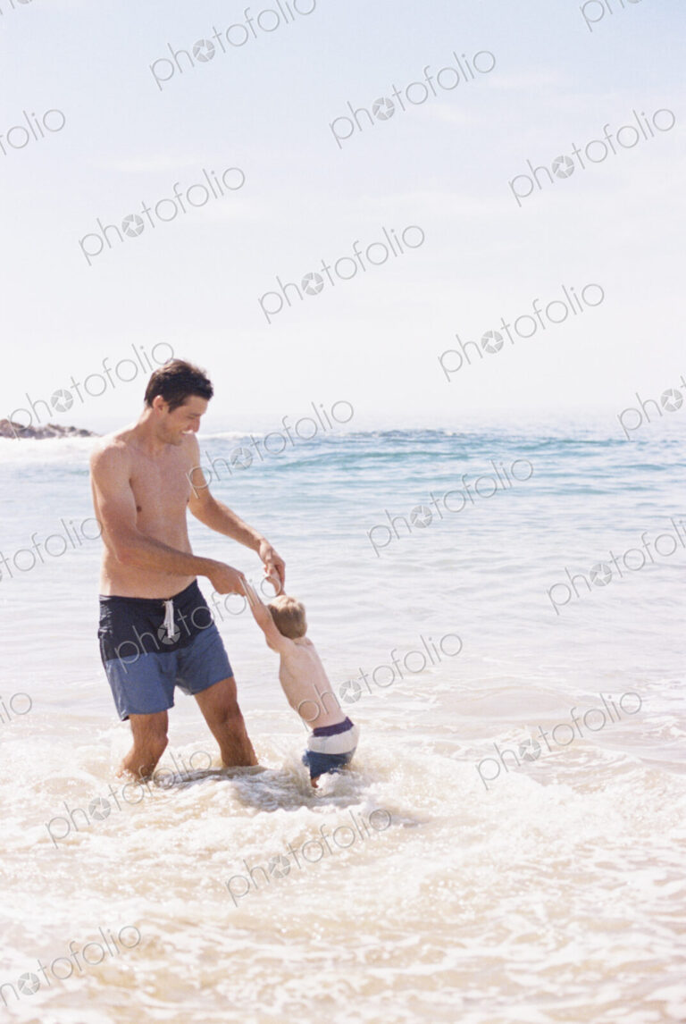 Man playing with his young son on the beach.
