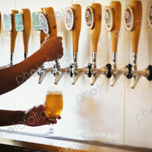 Man pulling a glass of beer from a tasting bar in a brewery.