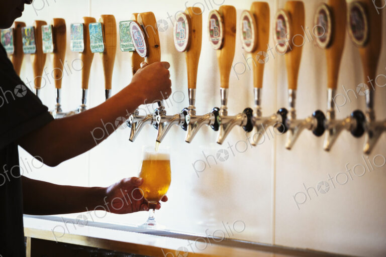Man pulling a glass of beer from a tasting bar in a brewery.