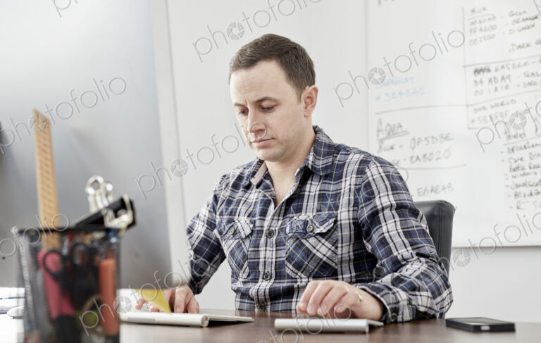 Man seated at a desk using a laptop computer.