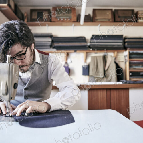 Man sewing a garment using an industrial sewing machine, at a family tailoring… Man sewing a garment using an industrial sewing machine, at a family tailoring…