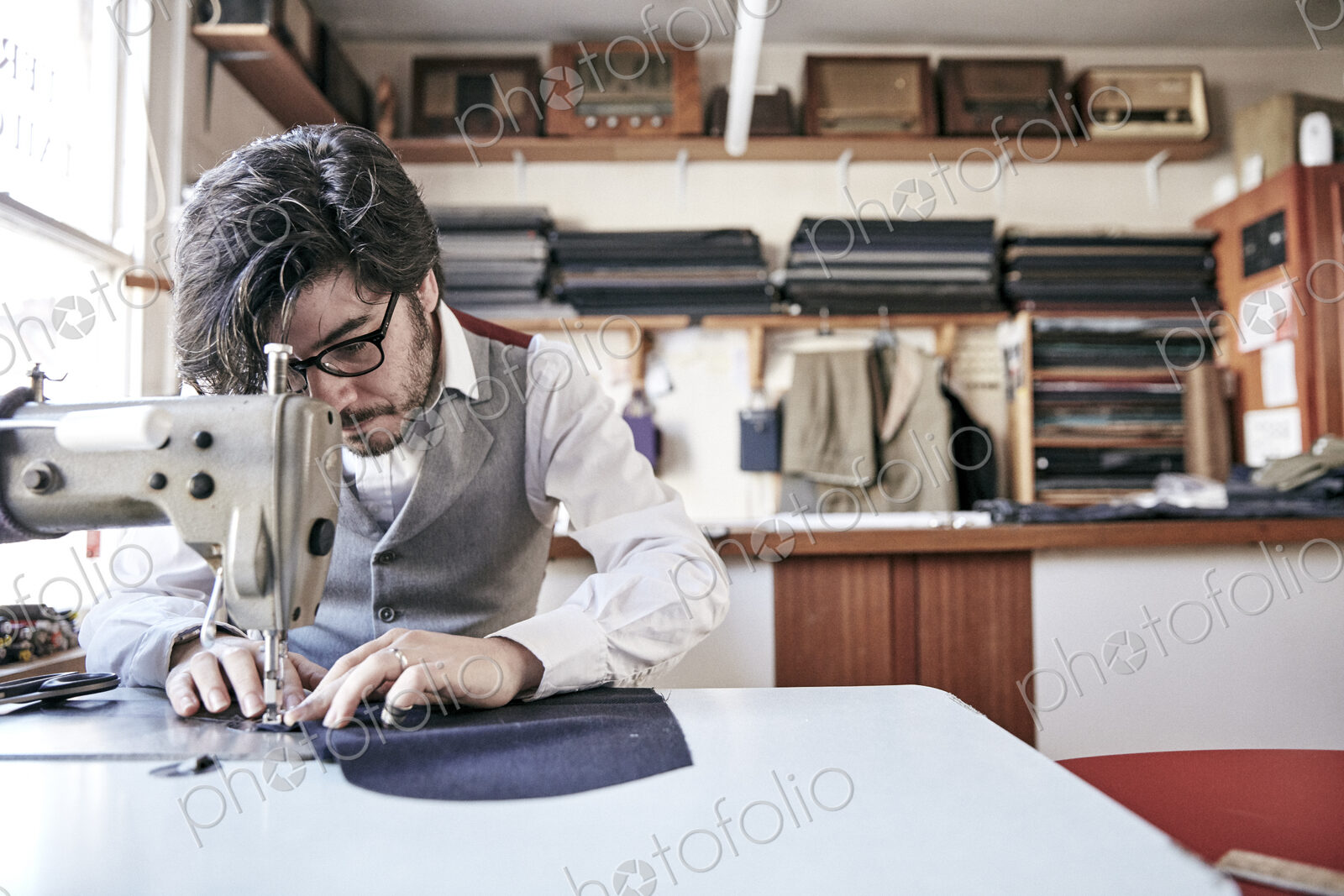 Man sewing a garment using an industrial sewing machine, at a family tailoring…