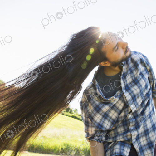 Man shaking out his very long black hair, tilting his head