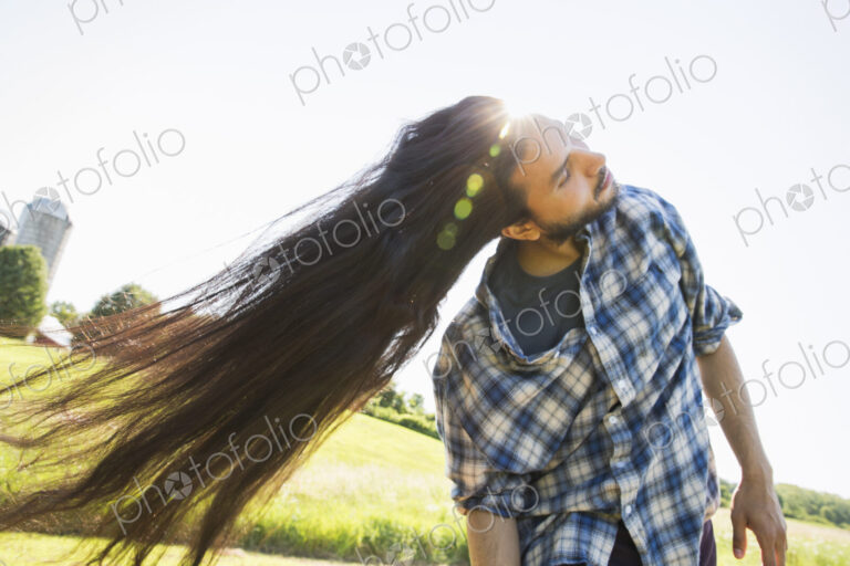 Man shaking out his very long black hair, tilting his head