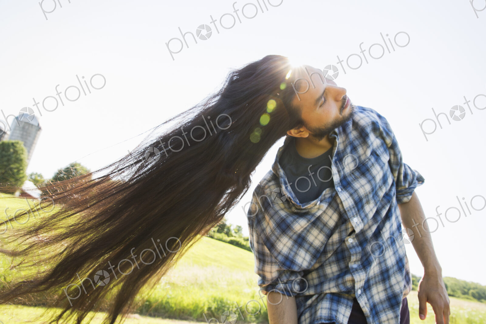 Man shaking out his very long black hair, tilting his head